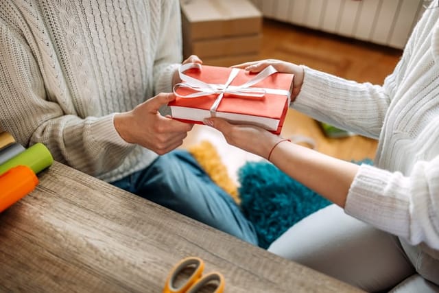 woman giving woman book as gift