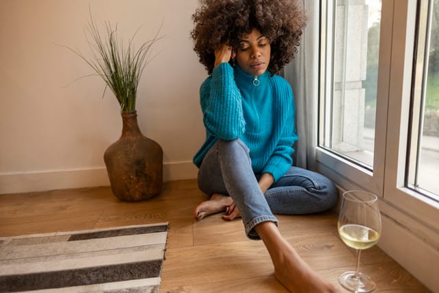 sad woman sitting with a glass of wine