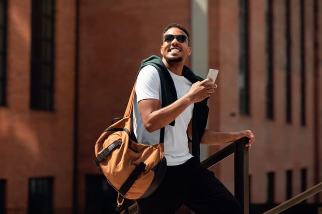 smiling man texting while walking down street