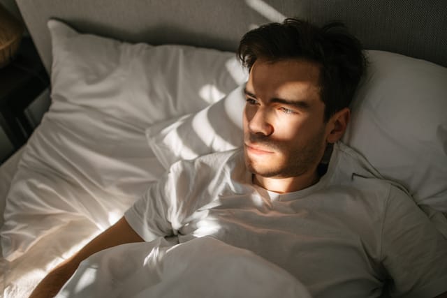 Man lying in a bed and waking up