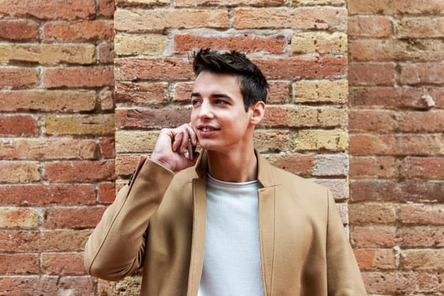 smiling man talking on phone against wall