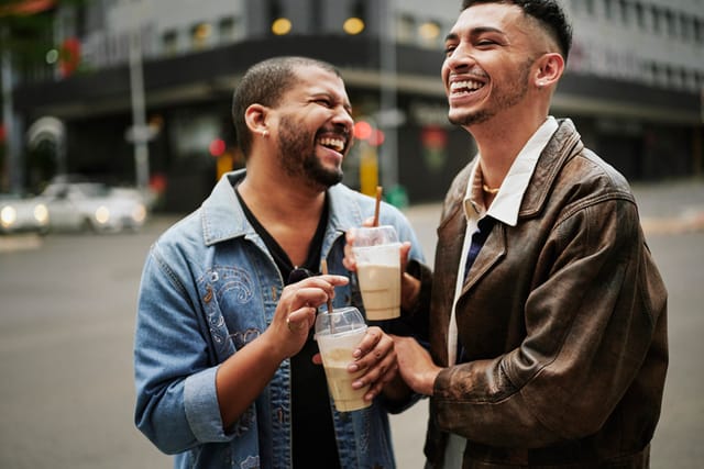 two men laughing and chatting on city street