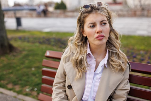 Young woman sitting on park bench and waiting