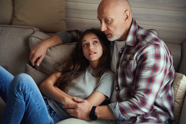 pre-teen girl with upset dad on couch