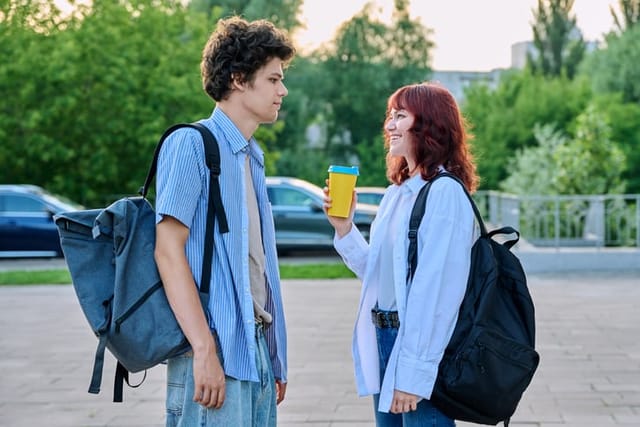 young man and woman with backpacks chatting