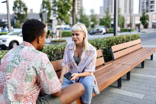 Multiracial man and woman sitting on the bench and talking