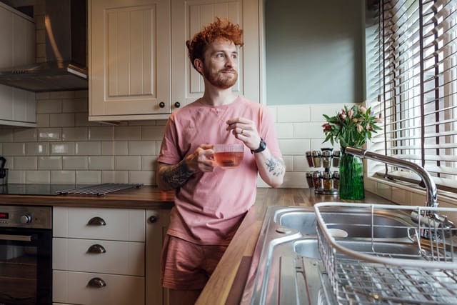 ginger man standing in kitchen with tea