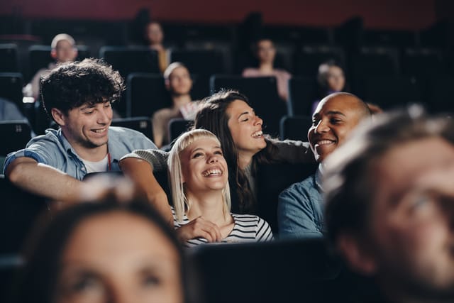 Happy couples communicating before a movie projection in cinema.