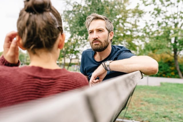 man and woman talking to each other on bench
