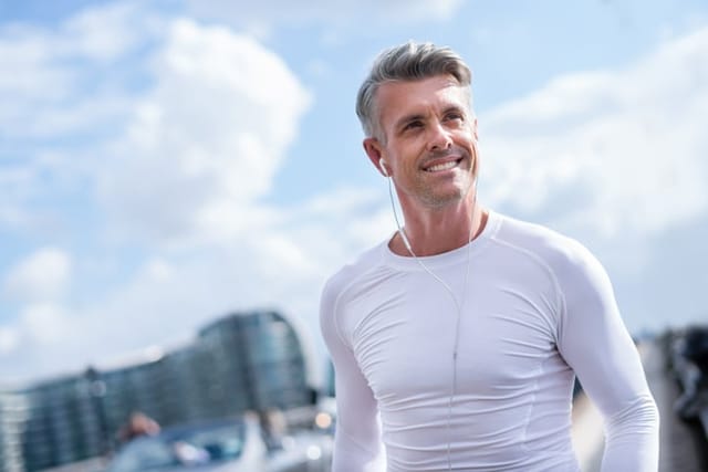 Happy man running outdoors and listening to music