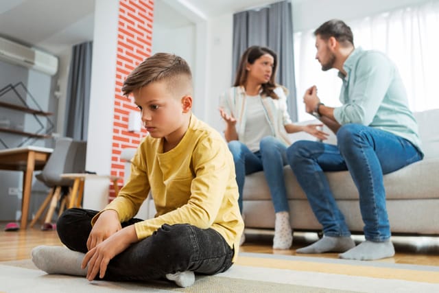 upset kid with parents fighting behind him