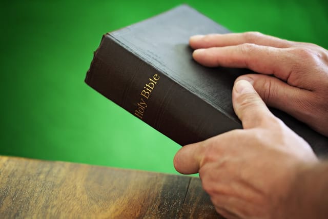 man's hand on bible