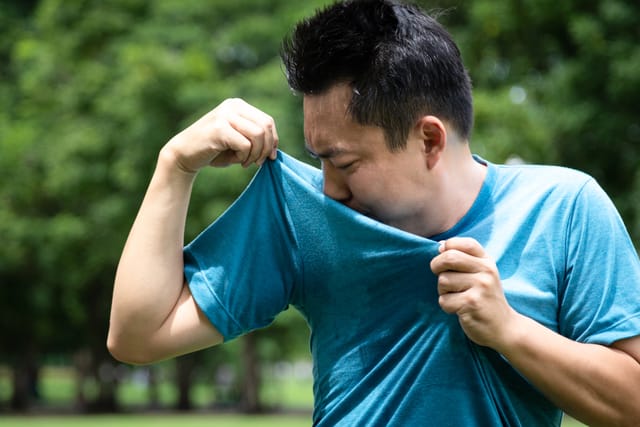 Young man smelling his underarms.