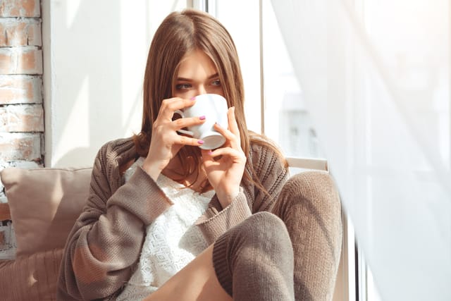 Woman having coffee at her window.