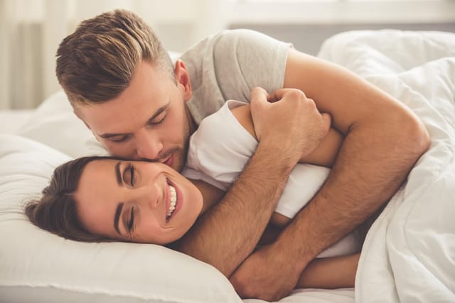 Young man and woman hugging in bed.