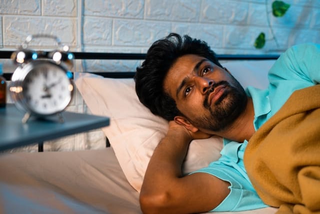 A man laying awake in bed.
