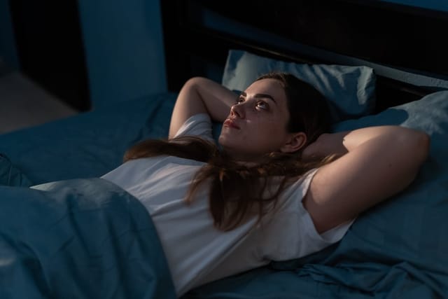 A woman laying awake in bed.