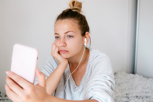 sad young girl texting in bed