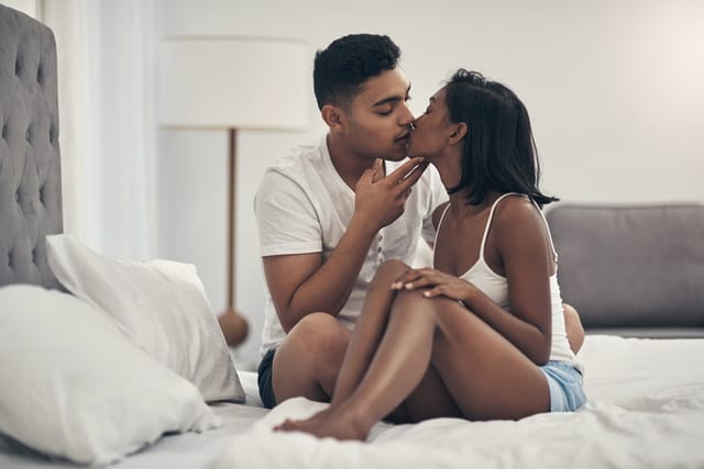 man kissing woman in bed
