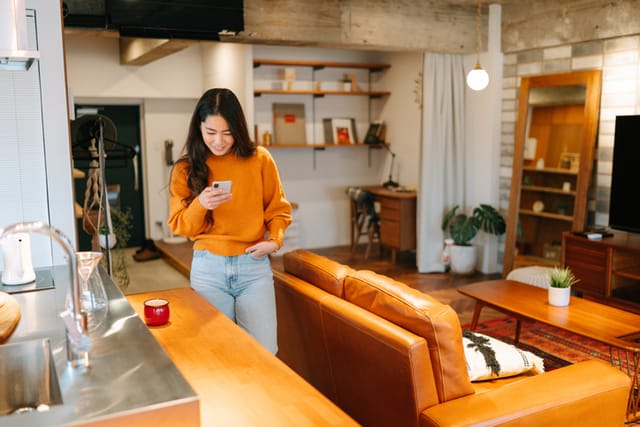 woman texting in orange sweater