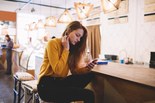 concerned woman texting at cafe bar