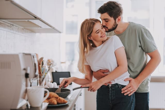 couple cuddling in kitchen over breakfast
