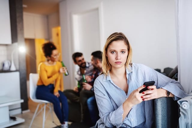 unhappy woman away from colleagues