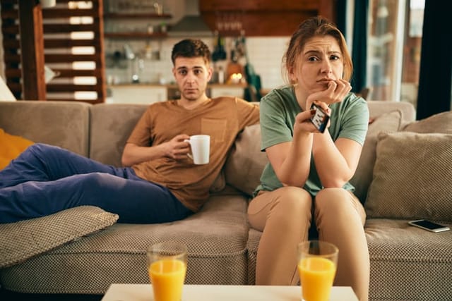couple bored sitting on couch watching tv