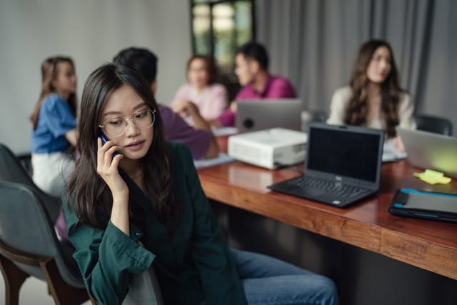 woman taking phone call during business meeting