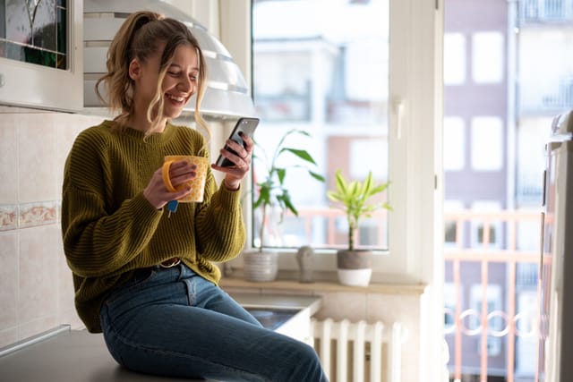 smiling woman texting in kitchen