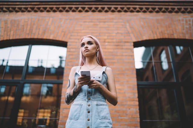 blonde tattooed woman texting outdoors