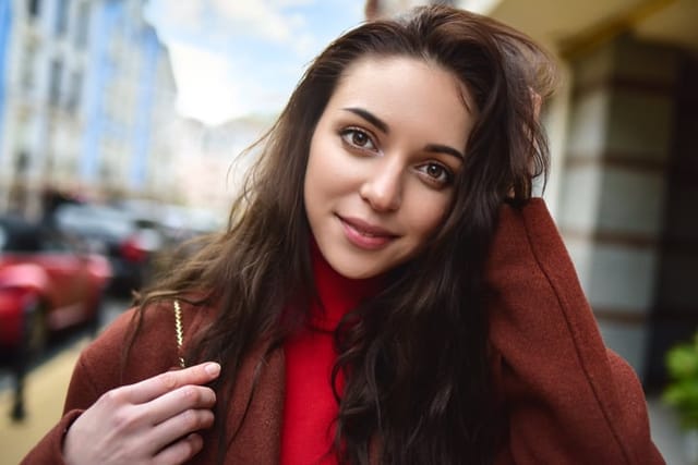 portrait of a fashionably dressed woman posing for the camera in a brown coat and red sweater