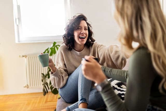 two female friends laughing on the couch