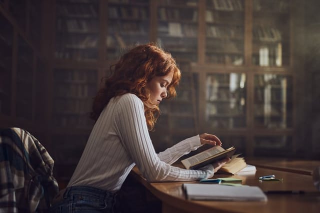 woman reading book in dark library