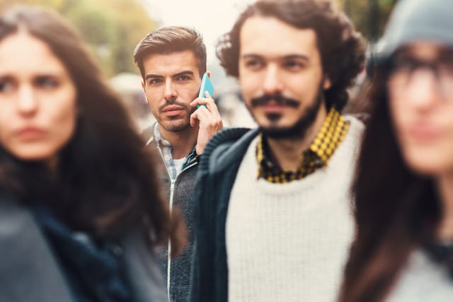 A man talking on the phone in a crowd.