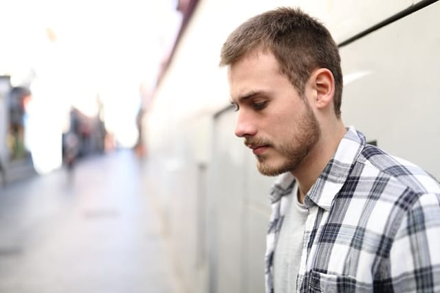 man outside standing against wall