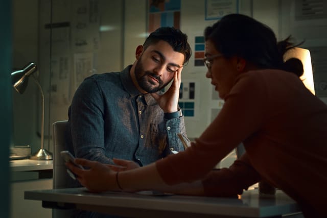 man touching his face listening to woman