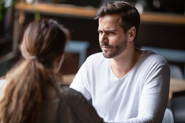 skeptical looking man talking to woman