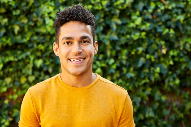 smiling man foliage background yellow sweater
