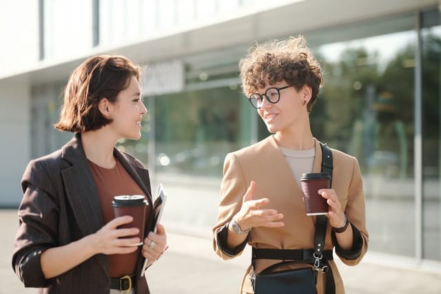 Two colleagues with drinks discussing working points.