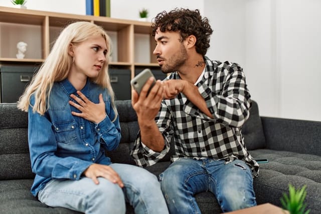 Young couple sitting on the sofa discussing at home.