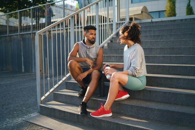 male female runner sitting on steps afer exercise