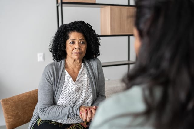 Serious mother listening to daughter at home or doing a psychology consultation