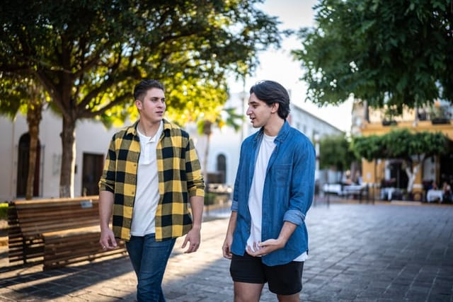 two male friends walking and talking in the park