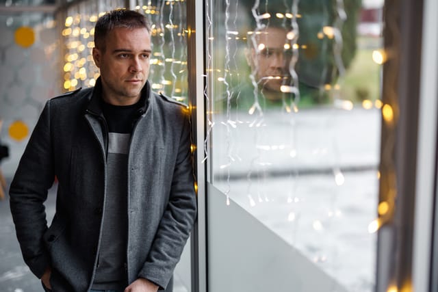Portrait of handsome man standing and looking through window at cafe