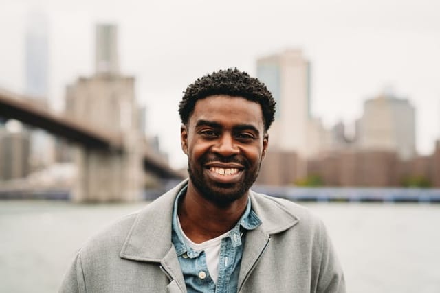Portrait of a cheerful millennial man in the city. Brooklyn Bridge in the background.