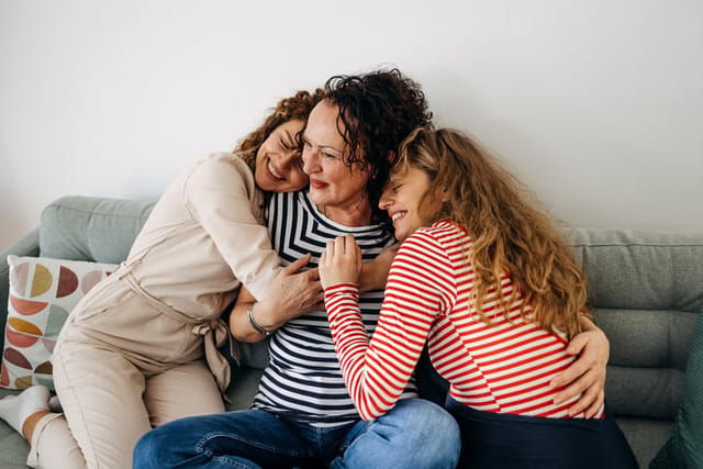 Portrait of mother with her daughters sitting on the sofa and looking at the camera