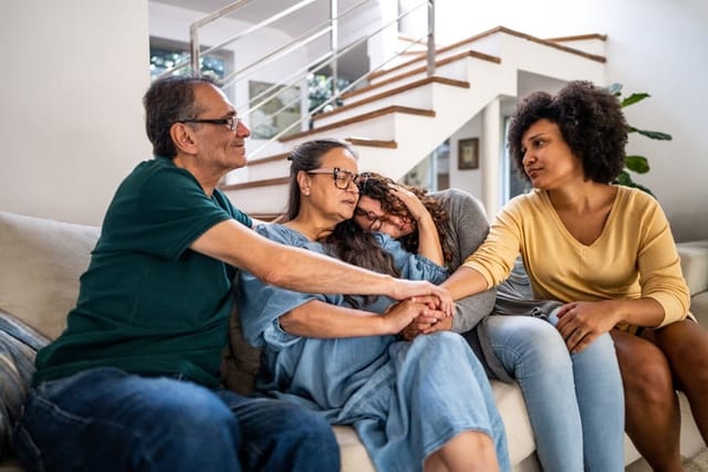 parents comforting daughter on couch