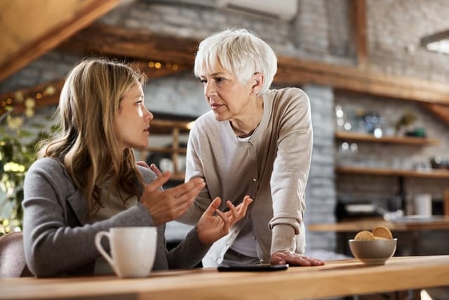 Single mature mother talking to her depressed adult daughter at home.