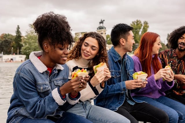 Friends eating lunch while laughing outside.